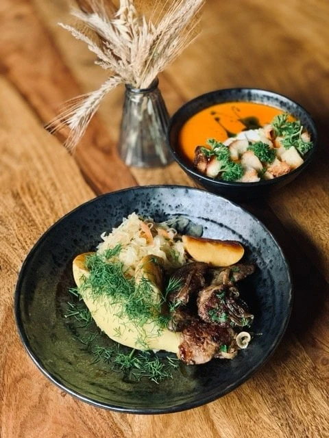 Danie obiadowe na talerzu i miska zupy na stole w restauracji.